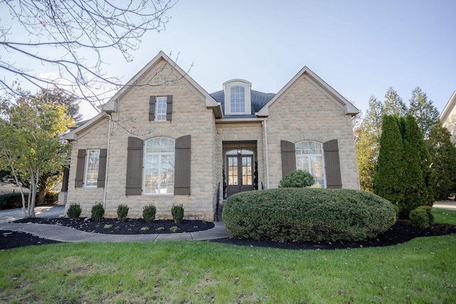 french country inspired facade featuring a front lawn and french doors