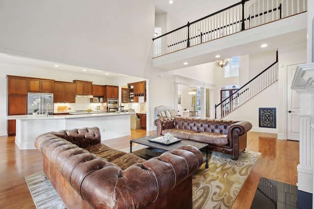 living room featuring a notable chandelier, light hardwood / wood-style flooring, decorative columns, and a high ceiling