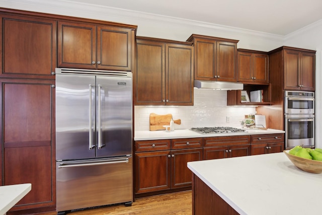 kitchen with crown molding, stainless steel appliances, light hardwood / wood-style flooring, and backsplash