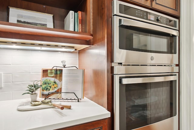 kitchen with stainless steel double oven and backsplash