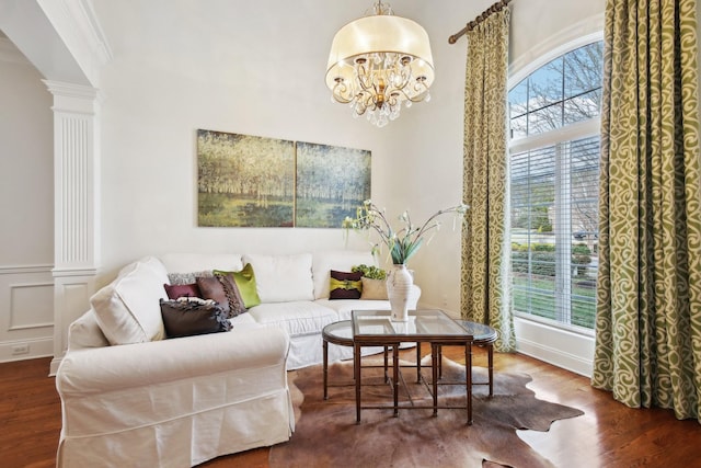 living room featuring hardwood / wood-style flooring, ornamental molding, decorative columns, and a notable chandelier