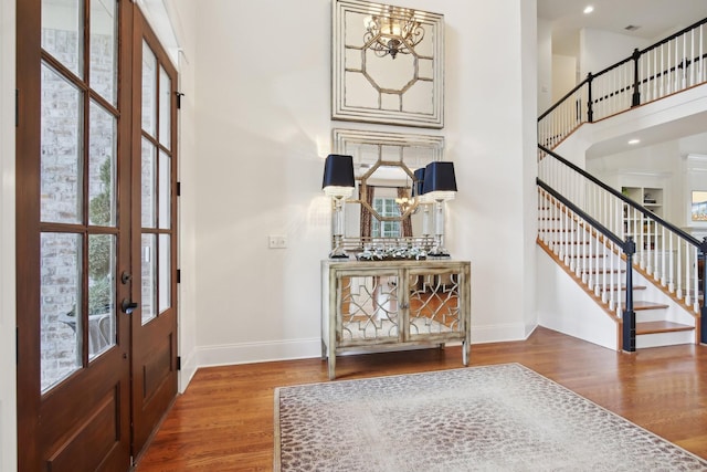 entryway featuring a high ceiling, wood-type flooring, a chandelier, and french doors