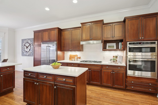 kitchen featuring stainless steel appliances, crown molding, a kitchen island, and light hardwood / wood-style flooring