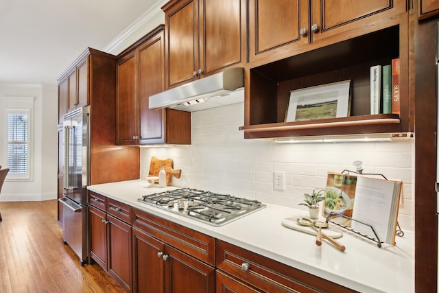 kitchen featuring crown molding, appliances with stainless steel finishes, light hardwood / wood-style flooring, and decorative backsplash