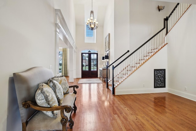 foyer featuring a high ceiling, a notable chandelier, light wood-type flooring, and french doors