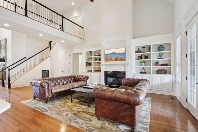 living room featuring light hardwood / wood-style floors, built in features, and a high ceiling