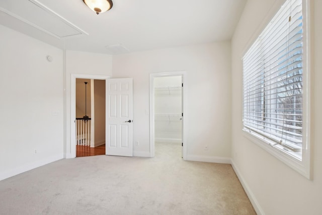 unfurnished bedroom with light colored carpet, a spacious closet, and a closet