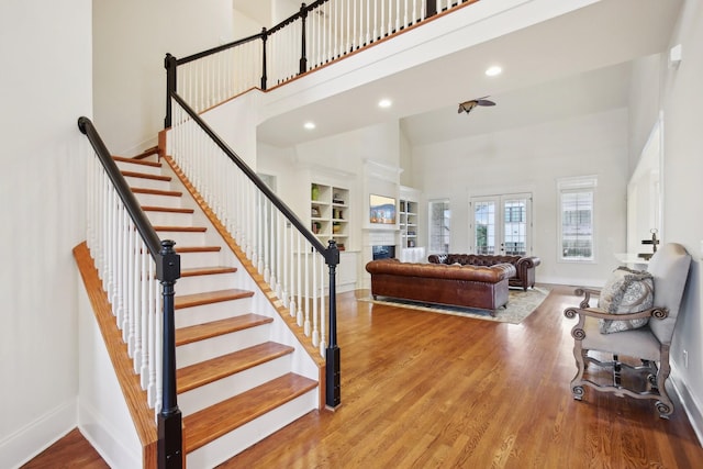 staircase featuring hardwood / wood-style flooring, a high ceiling, built in features, and french doors