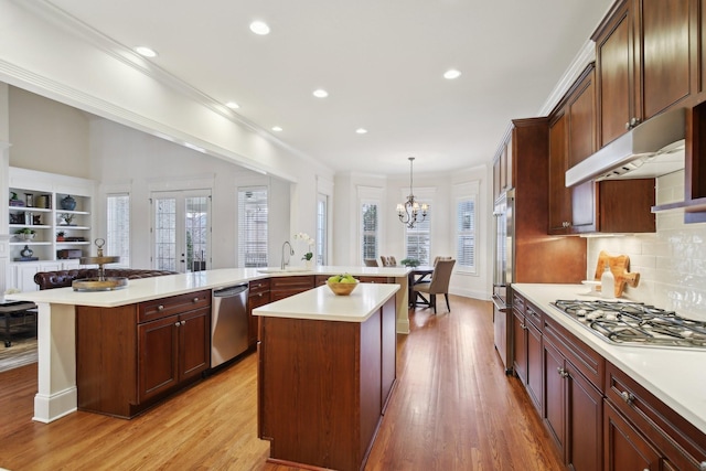 kitchen with pendant lighting, sink, stainless steel appliances, a center island, and light hardwood / wood-style floors