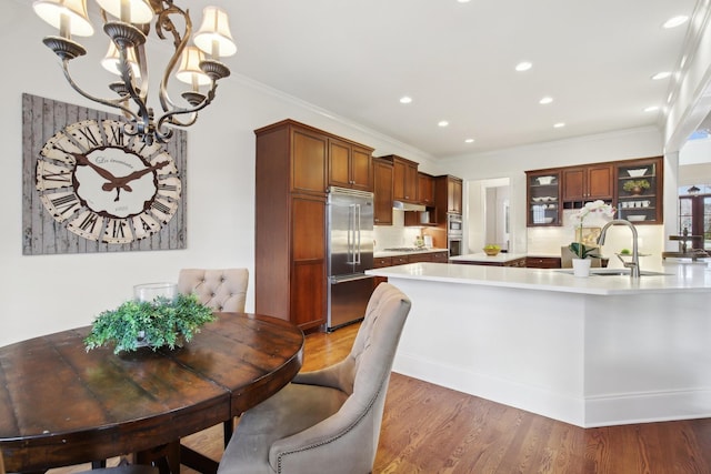 kitchen with sink, appliances with stainless steel finishes, dark hardwood / wood-style flooring, kitchen peninsula, and pendant lighting