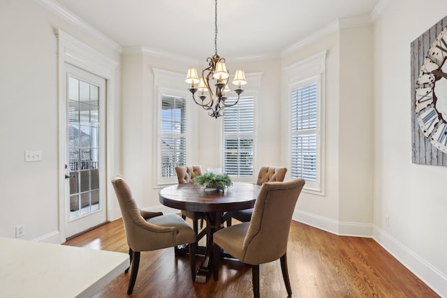 dining area with a notable chandelier, crown molding, and wood-type flooring