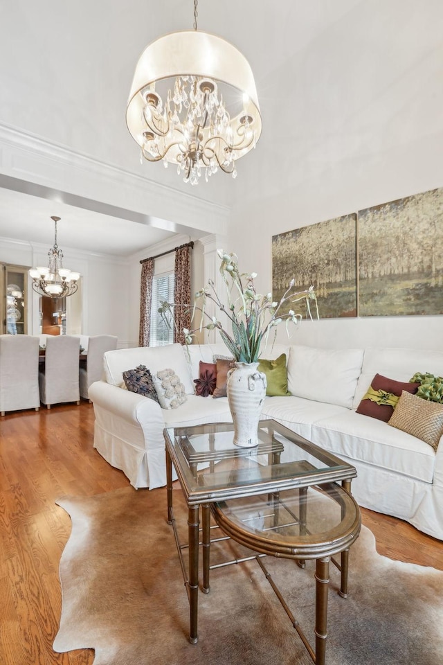 living room featuring hardwood / wood-style flooring, crown molding, and a notable chandelier