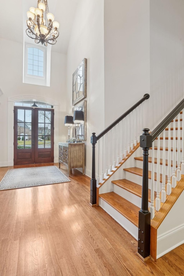 foyer entrance featuring an inviting chandelier, plenty of natural light, high vaulted ceiling, and light wood-type flooring