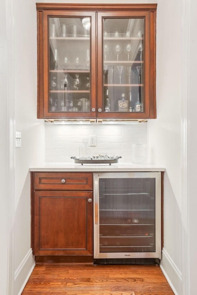 bar featuring hardwood / wood-style floors, backsplash, and beverage cooler