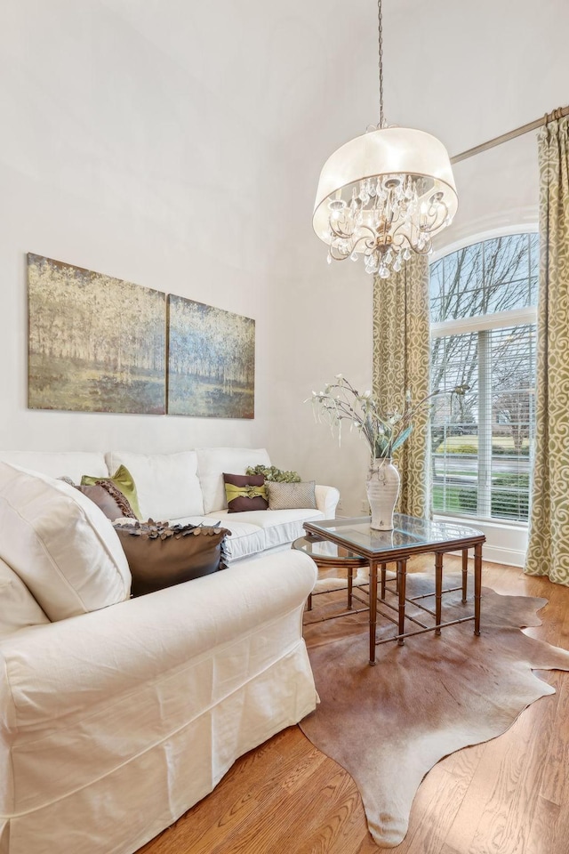 living room with an inviting chandelier, a towering ceiling, and wood-type flooring