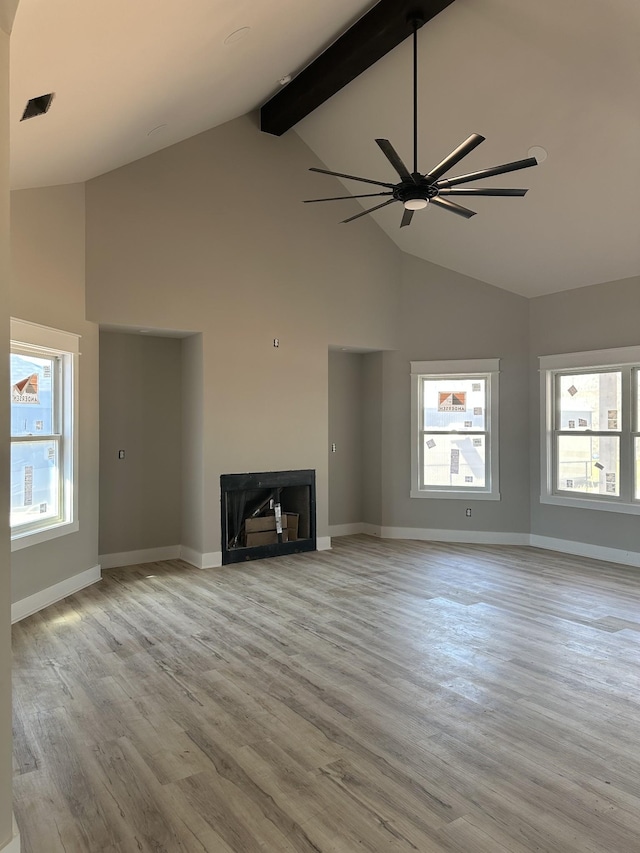 unfurnished living room with wood finished floors, beamed ceiling, a fireplace, and baseboards