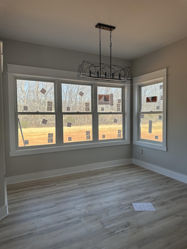 unfurnished dining area featuring baseboards and wood finished floors