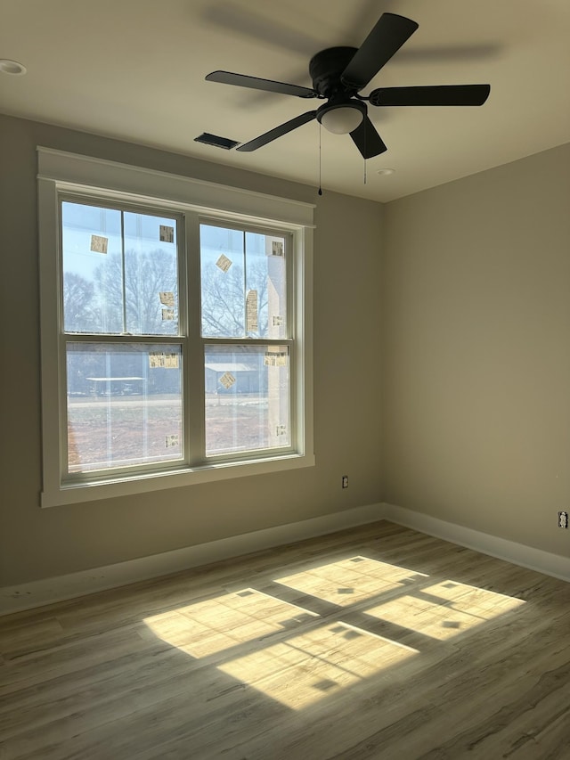 spare room with a ceiling fan, wood finished floors, and baseboards