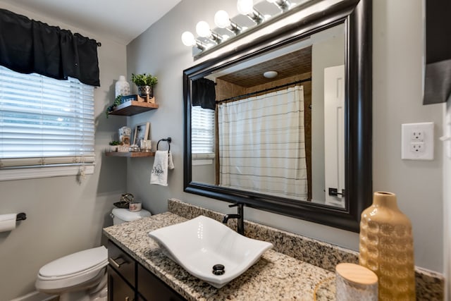 bathroom featuring plenty of natural light, curtained shower, toilet, and vanity