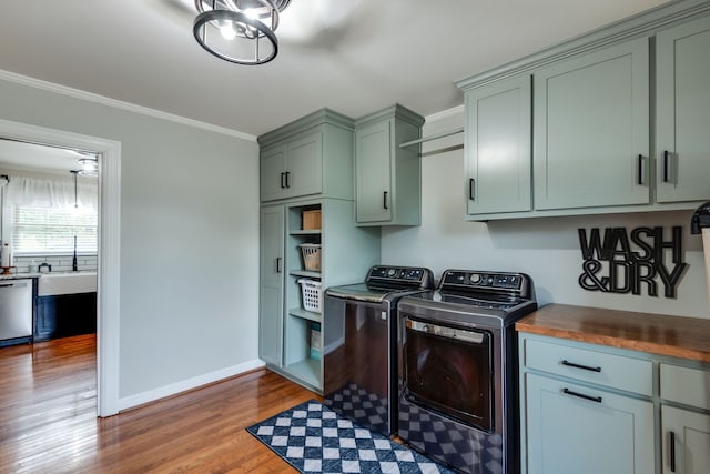 laundry area with cabinets, crown molding, sink, separate washer and dryer, and hardwood / wood-style floors