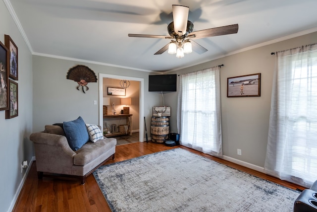 living area with hardwood / wood-style flooring, ceiling fan, and ornamental molding