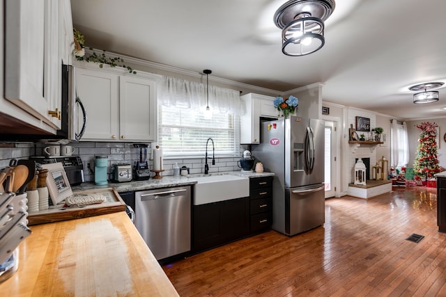 kitchen with wooden counters, white cabinets, stainless steel appliances, and wood-type flooring