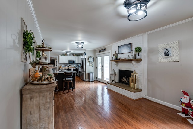 living room featuring hardwood / wood-style flooring, crown molding, and a brick fireplace