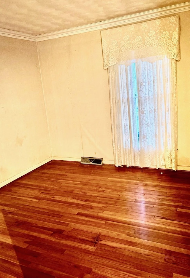 spare room featuring wood-type flooring and ornamental molding