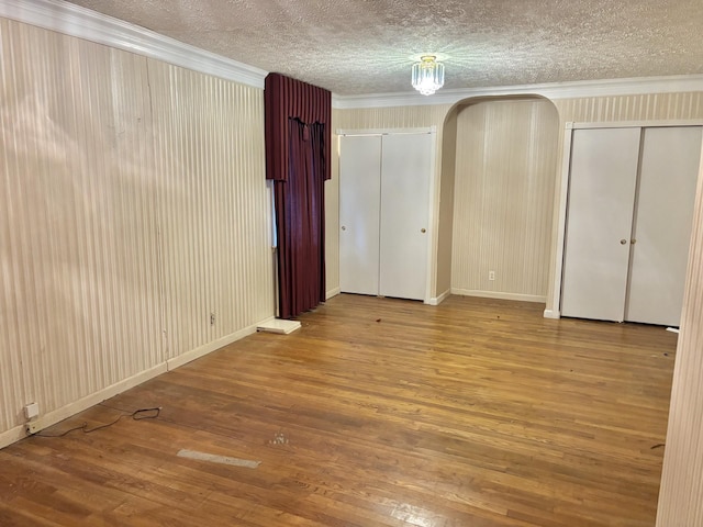 spare room featuring crown molding, a textured ceiling, and hardwood / wood-style flooring