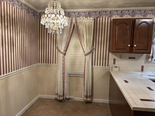 interior space with tile countertops, dark tile patterned floors, dark brown cabinets, and a notable chandelier