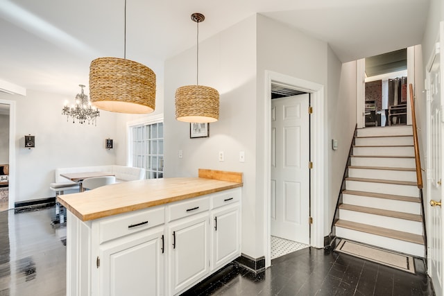 kitchen featuring white cabinetry, dark wood-type flooring, hanging light fixtures, and wood counters