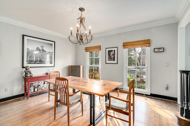 dining room with light hardwood / wood-style floors, ornamental molding, and a notable chandelier