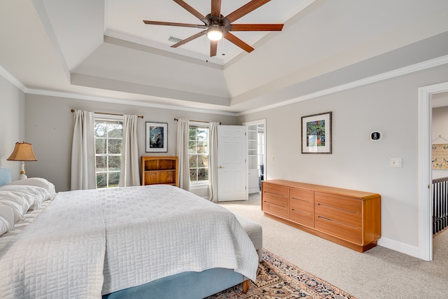 carpeted bedroom with a tray ceiling, ceiling fan, and crown molding