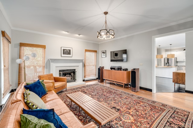 living room with a fireplace, crown molding, hardwood / wood-style floors, and a chandelier