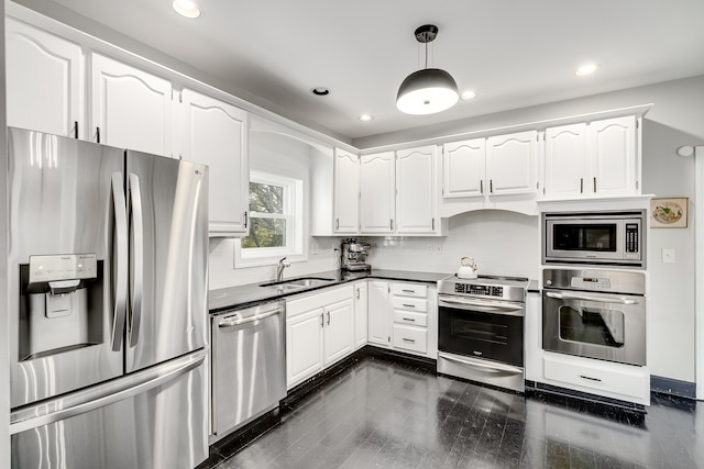 kitchen with white cabinetry, stainless steel appliances, hanging light fixtures, and dark wood-type flooring