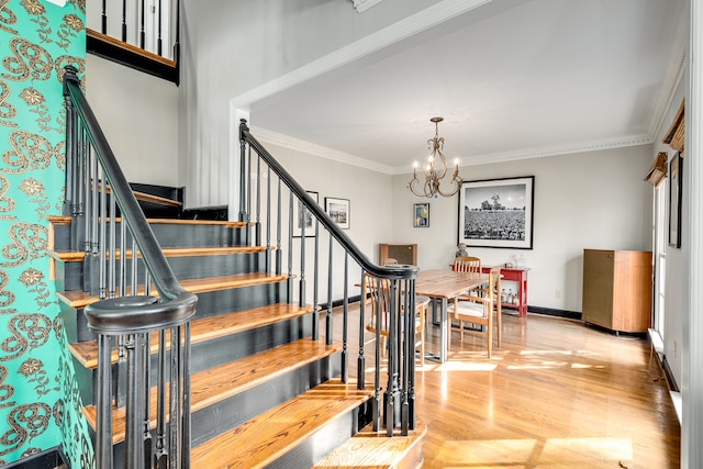 stairs with hardwood / wood-style flooring, ornamental molding, and an inviting chandelier