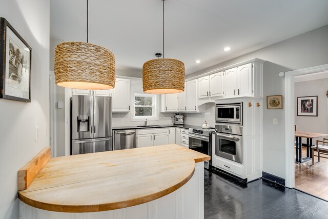 kitchen featuring stainless steel appliances, sink, decorative light fixtures, dark hardwood / wood-style floors, and white cabinetry