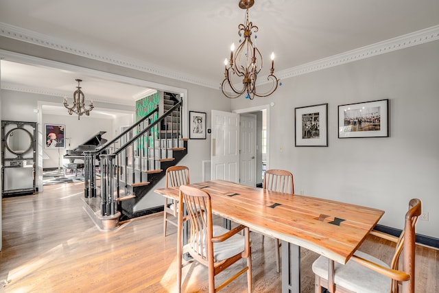 dining space with ornamental molding, a notable chandelier, and light wood-type flooring