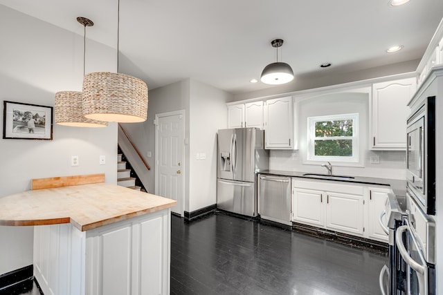 kitchen featuring appliances with stainless steel finishes, decorative light fixtures, and white cabinetry