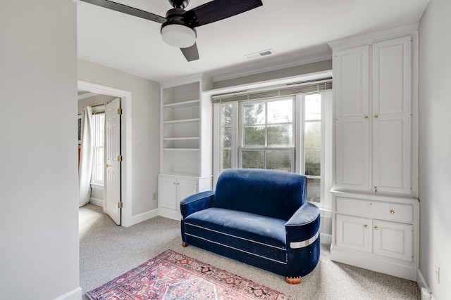 living area with light colored carpet, ceiling fan, and ornamental molding