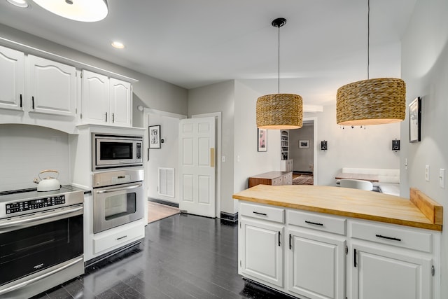 kitchen featuring appliances with stainless steel finishes, pendant lighting, white cabinets, dark hardwood / wood-style floors, and butcher block counters