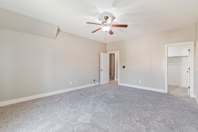 unfurnished bedroom with carpet flooring, a walk in closet, a closet, and ceiling fan