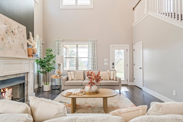 living room featuring a tile fireplace, a high ceiling, and dark hardwood / wood-style flooring