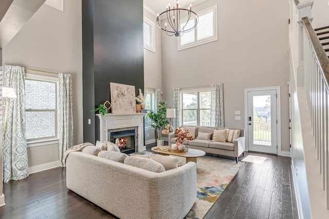 living room with a towering ceiling, dark hardwood / wood-style floors, and an inviting chandelier