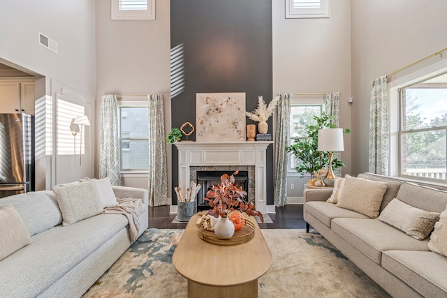 living room with light hardwood / wood-style floors, a fireplace, a wealth of natural light, and a high ceiling