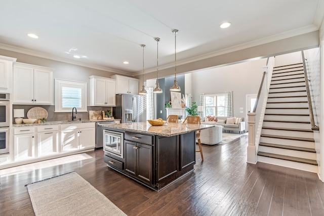 kitchen featuring white cabinets, a center island, dark wood-type flooring, and appliances with stainless steel finishes