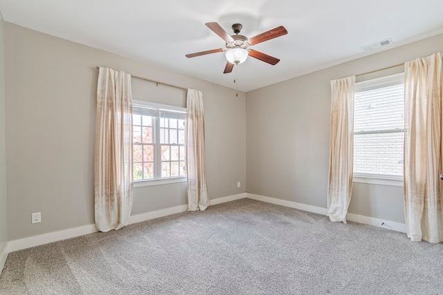 empty room featuring ceiling fan, carpet floors, and a wealth of natural light