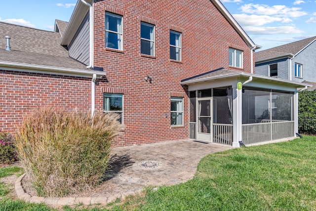 rear view of property with a lawn, a sunroom, and a patio area