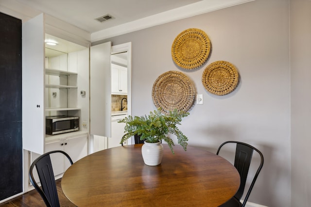 dining area featuring dark hardwood / wood-style flooring and ornamental molding