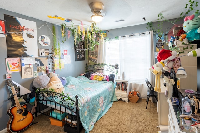 carpeted bedroom with ceiling fan and a textured ceiling